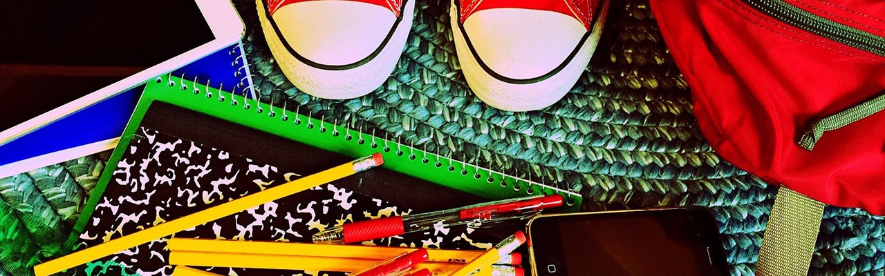 Child shoes standing near school supplies