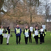 Litter Campaign 2018 - Photo 6 Children in high-vis vests walking through the park holding campaign posters