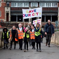 Litter Less Campaign 2018 14 Children marching across bridge in Abbey Park with "Save Our City" banner
