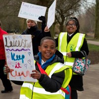 Litter Less Campaign 2018 20 Smiling boy in high-vis vest walking with a sign which reads "Leicester - Keep it clean"
