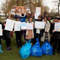 Litter Less Campaign 2018 29 Filbert Fox mascot with his hands in the air, celebrating next to group of volunteers holding campaign posters