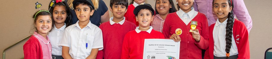 Lancaster School children holding an air quality award certificate with teachers behind them.